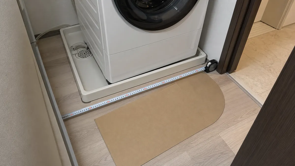 防水パンと前方スペースをメジャーで測る洗面所