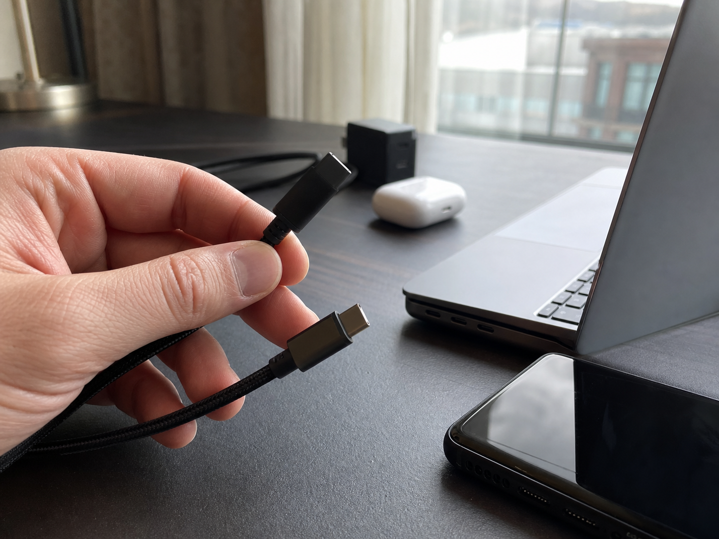 USB-CケーブルとUSB-Aケーブルの端子を出張用の机で見比べる場面